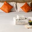 Hotel bed spread set up with orange pillows.