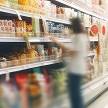 Grocery store aisle with people blurred to depict busy environment.