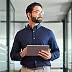Man in office holds tablet.