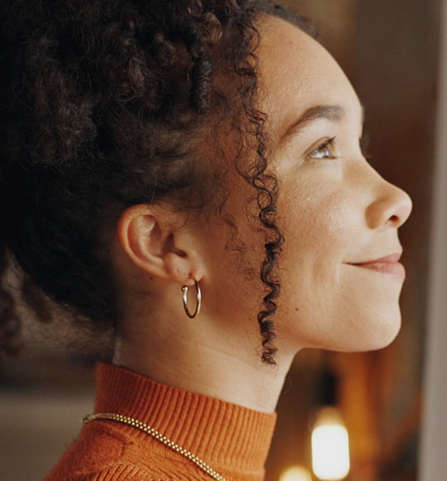Close up of woman looking out window with gold hoop earring.