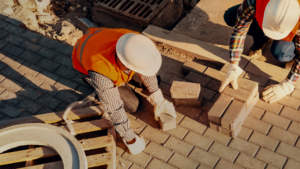 Overhead view of two construction workers in safety vest laying bricks.