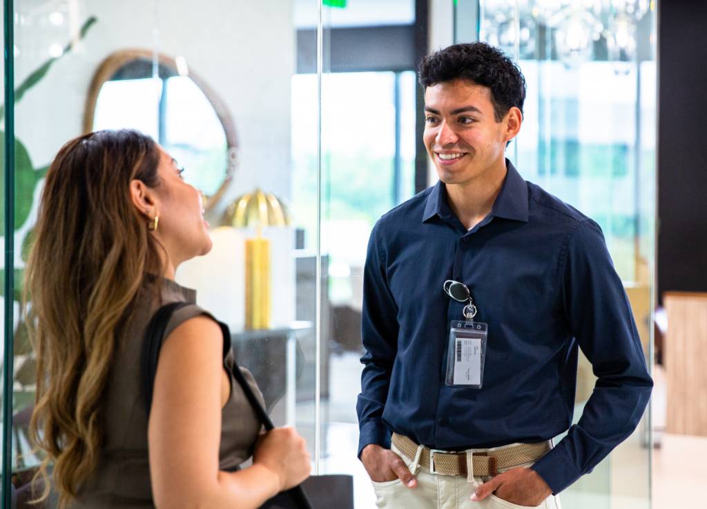 Man wearing security badge in modern office smiles at woman