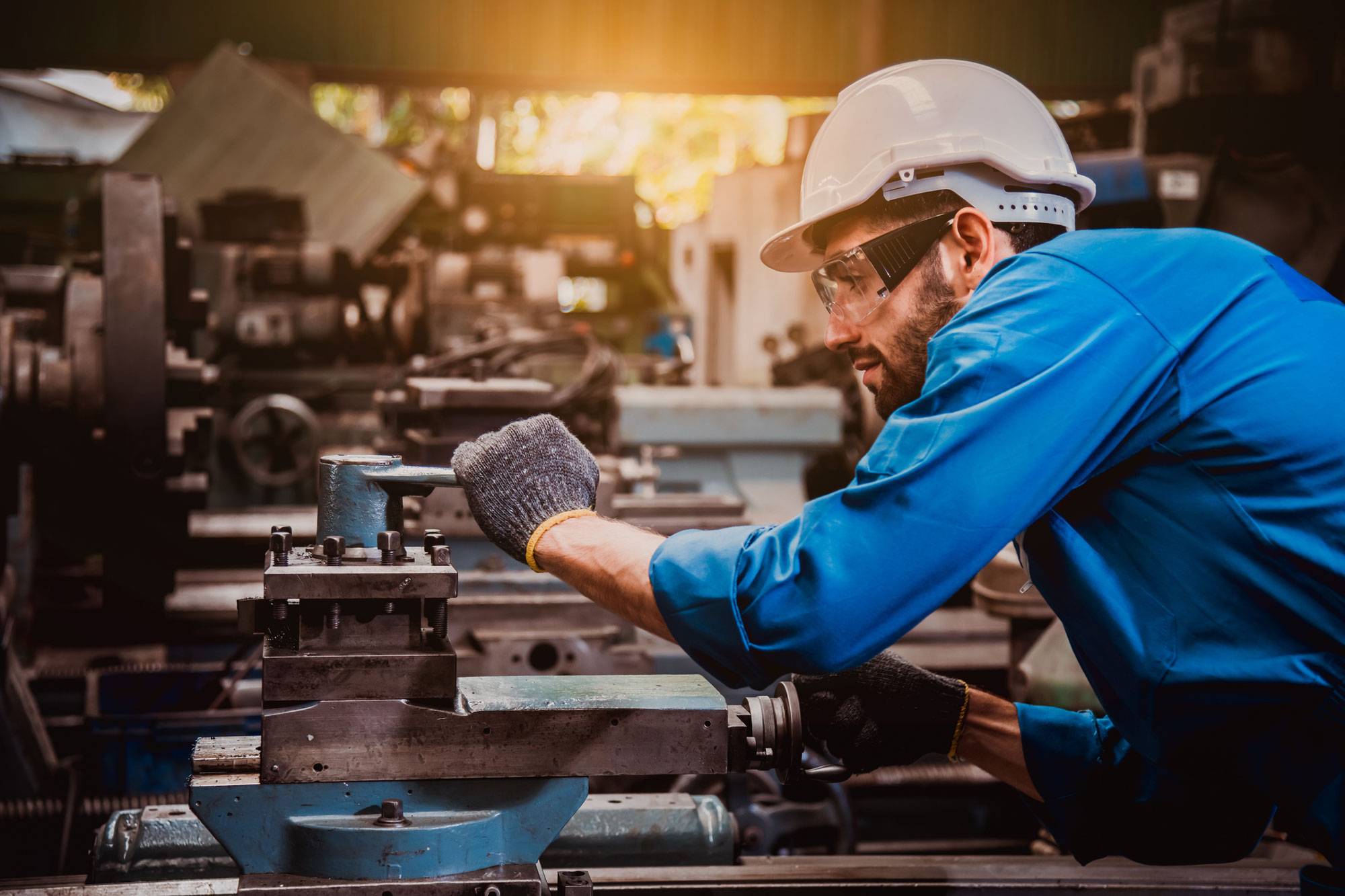Man in safety glasses, gloves and hard hat works machine operated tool