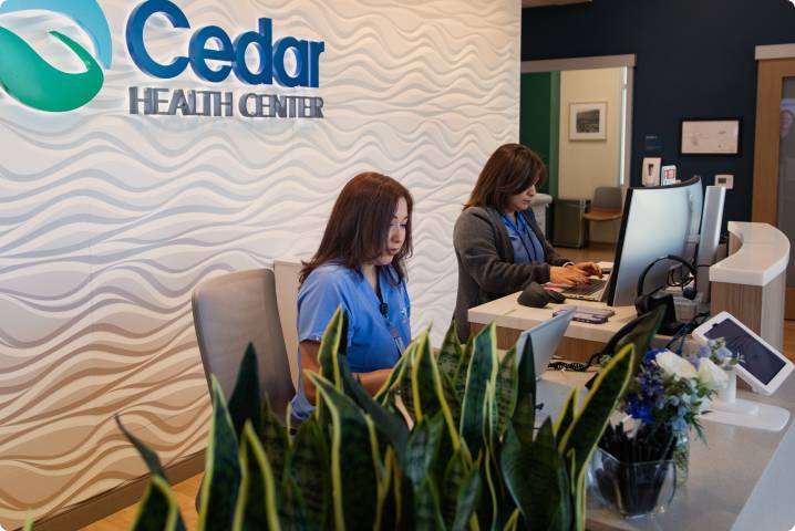 Two receptionists at medical desk for Cedar Health Center.