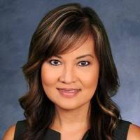 Headshot of woman in front of staged blue background.