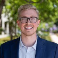 Headshot of man in glasses and blue blazer.