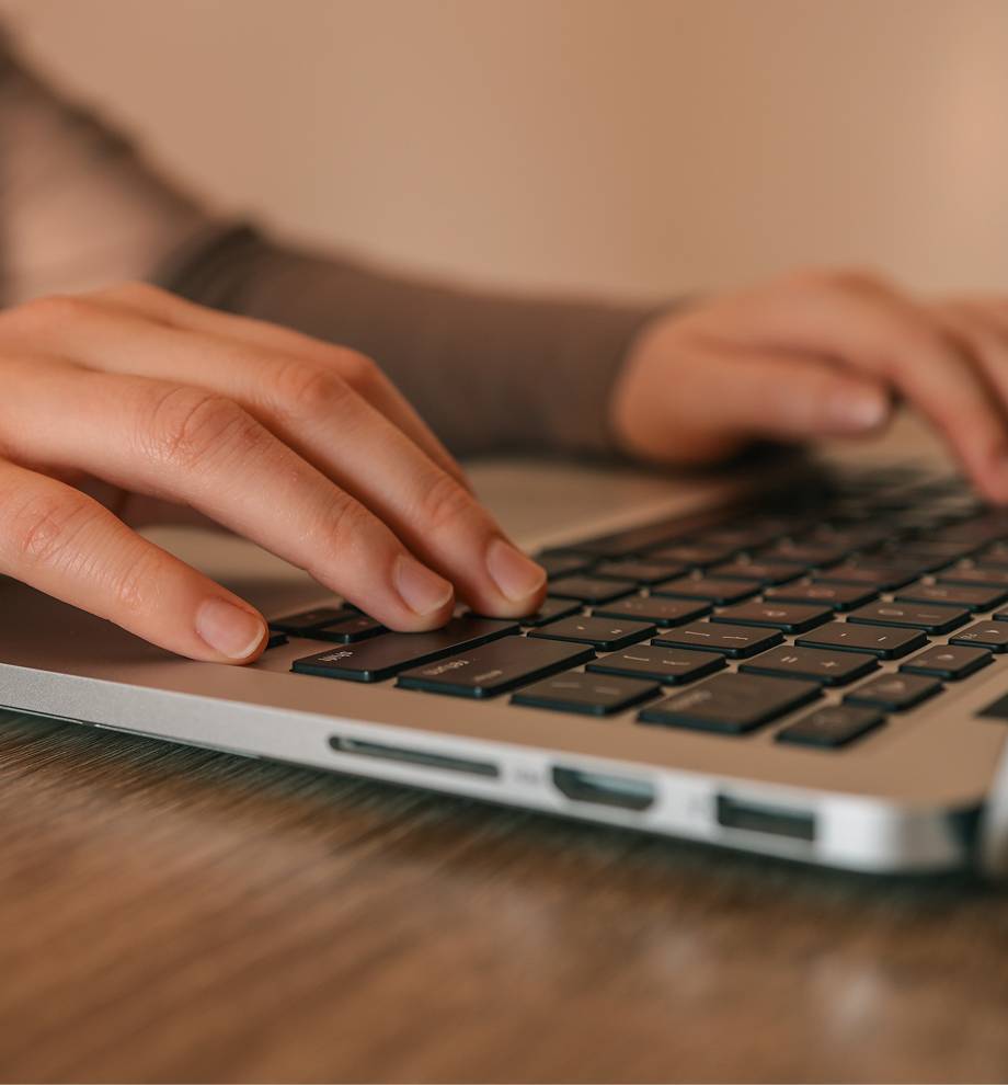 Two hands rest on a macbook keyboard.