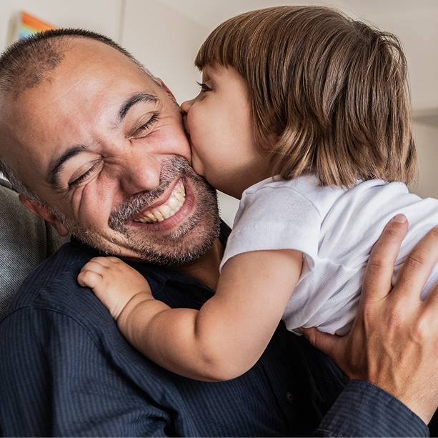 Older man holds granddaughter to face as she gives him a kiss.