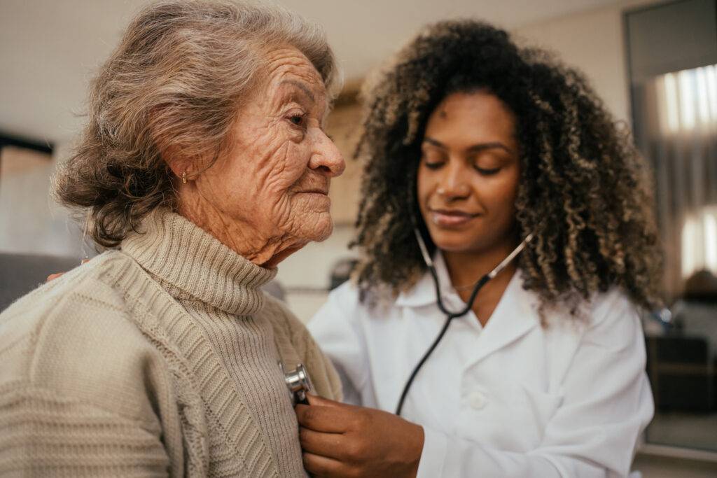 Doctor places stethoscope over older woman's sweater.