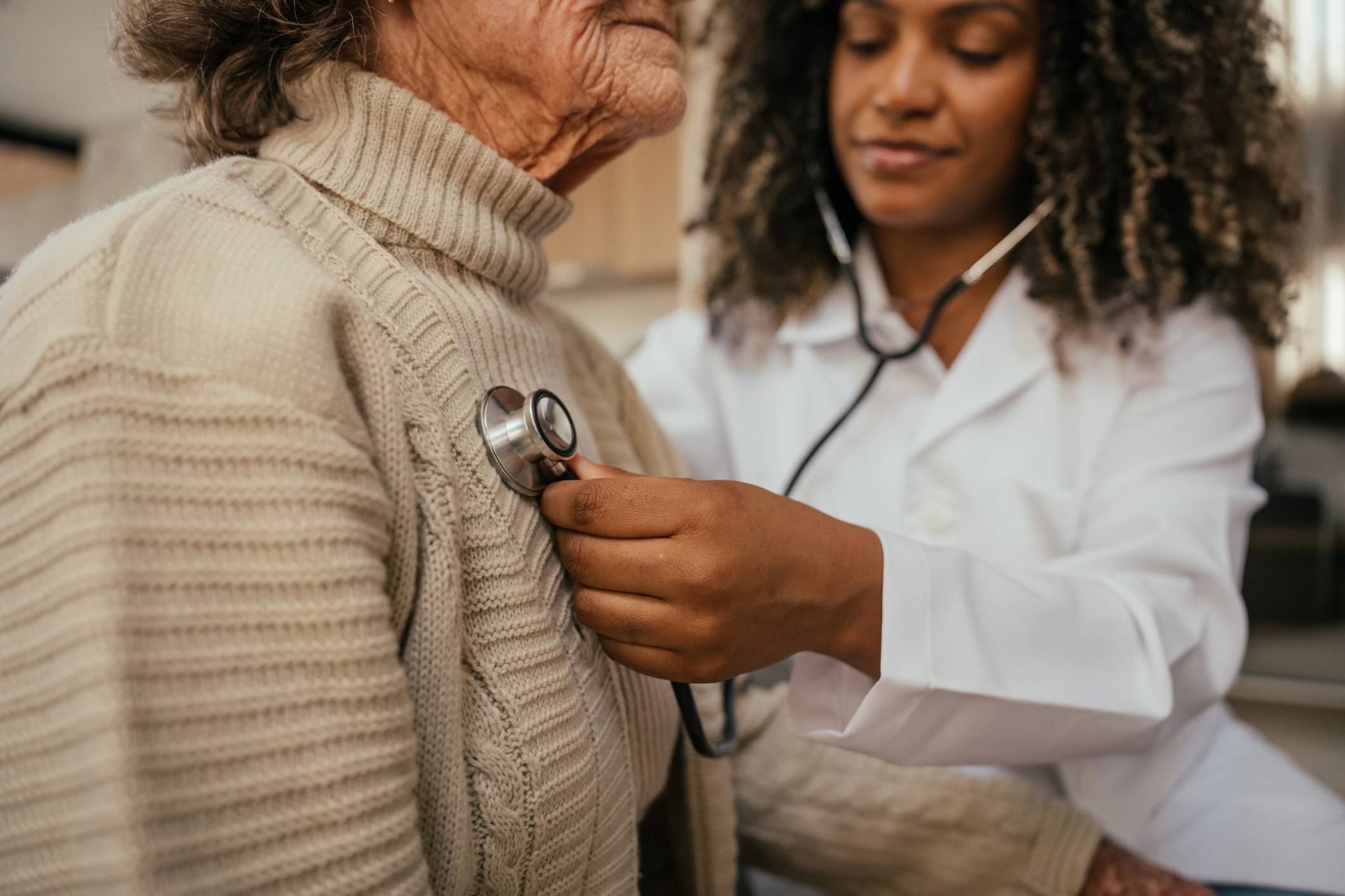 Doctor places stethoscope over older woman's sweater.