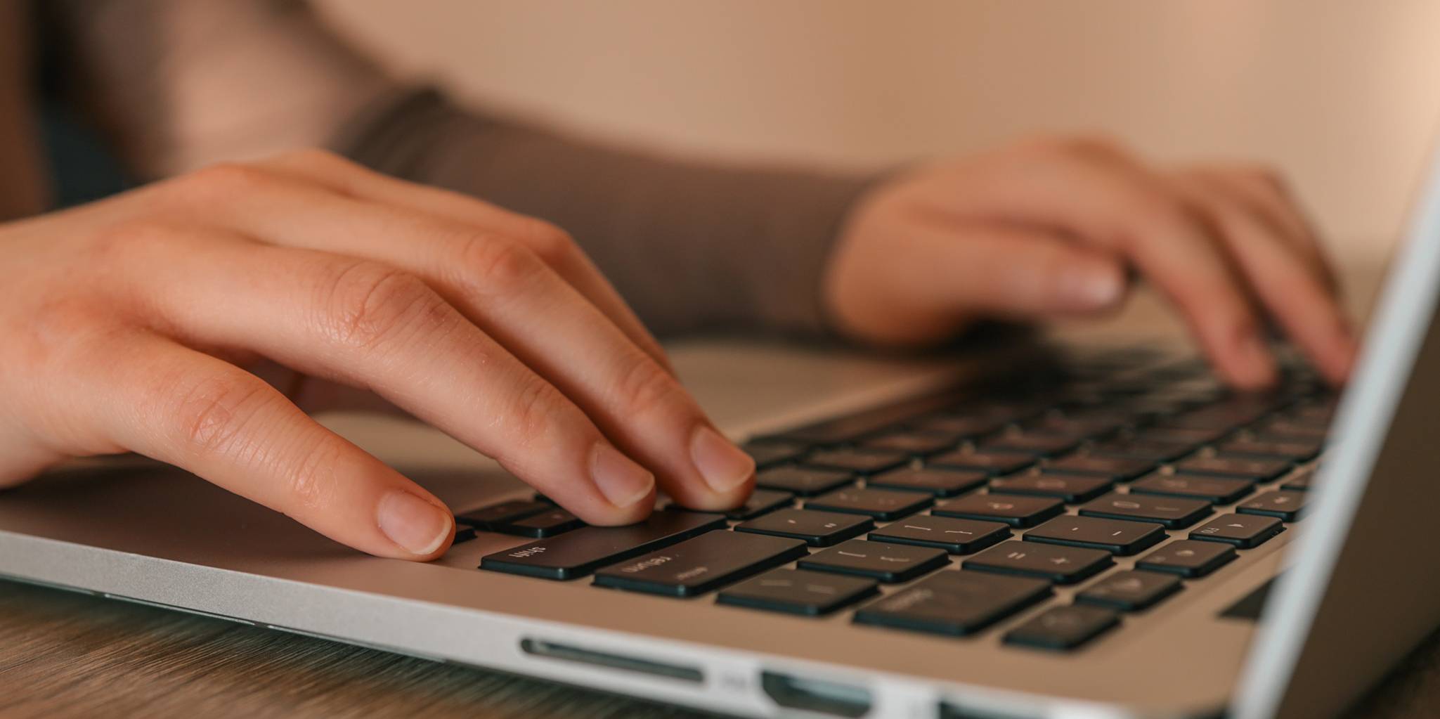 Two hands rest on a macbook keyboard.