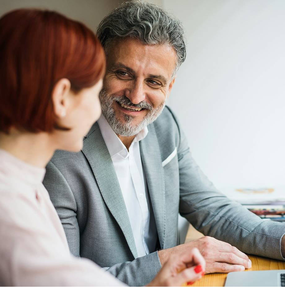 Man in gray blazer meets with red haired female client.
