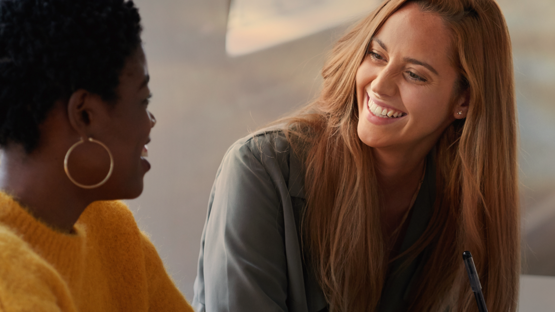 Two women sitting face to face and smiling.