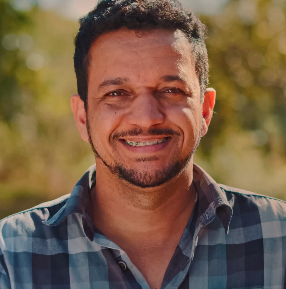 Close up of man in braces standing in front of a farm field.