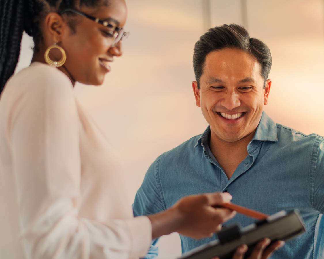 Woman in white shirt points to table, while man in button up smiles in agreement.