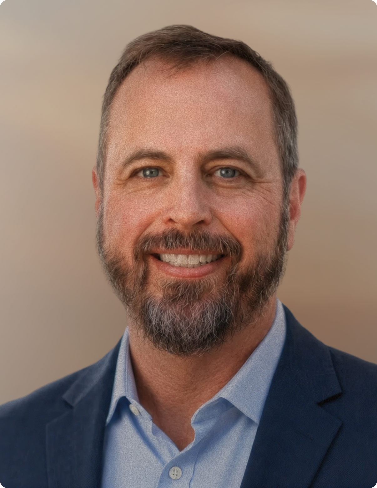 Headshot of man in front of white background, wearing blue blazer.