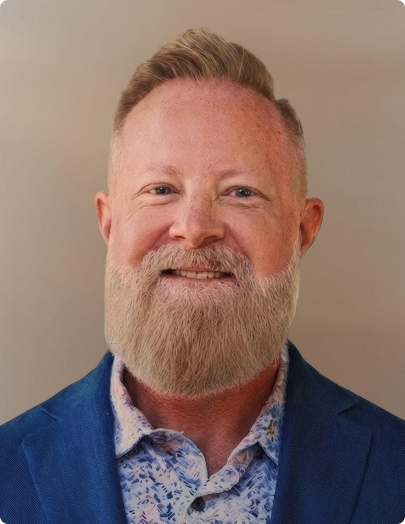 Headshot of man in front of white background, wearing blue blazer.