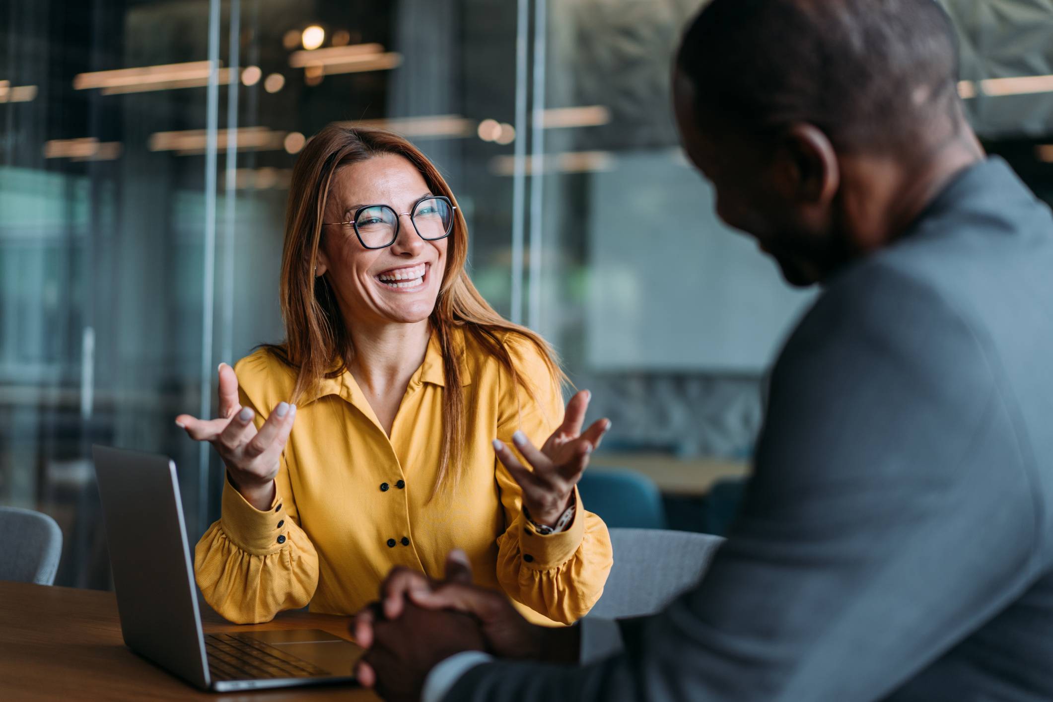 Two business woman sit down in front of laptop to share ideas.