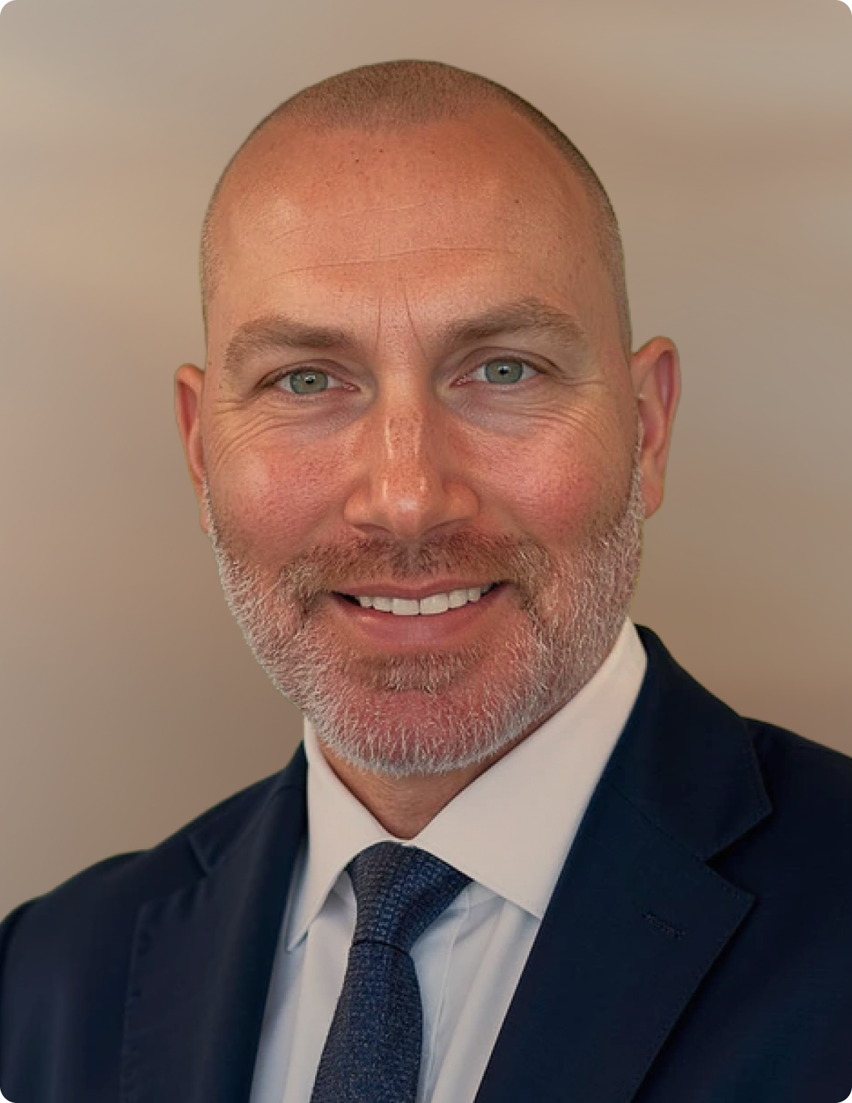 Headshot of man in front of white background, wearing blue blazer.