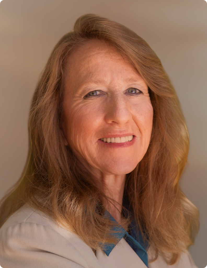 Headshot of woman in front of white background, wearing dress shirt.