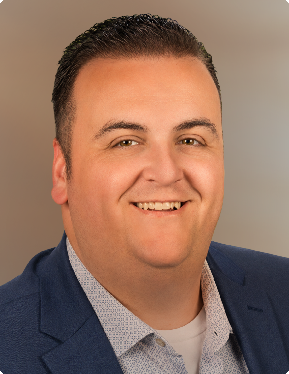 Headshot of man in front of white background, wearing blue blazer.