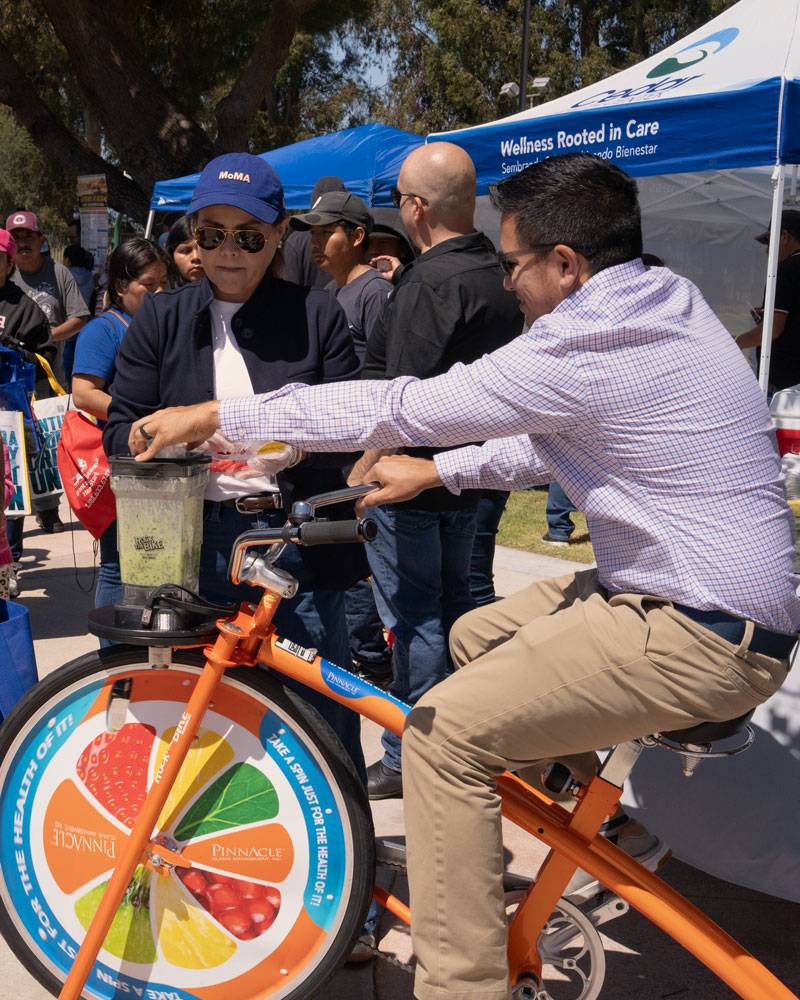 Man on orange bike that is powering blender in front of it.