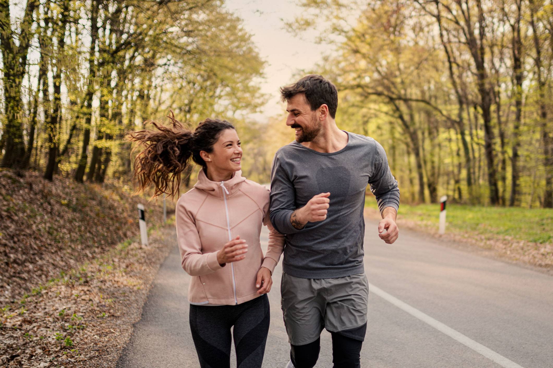 Man and woman running side by side and fall weather attire.